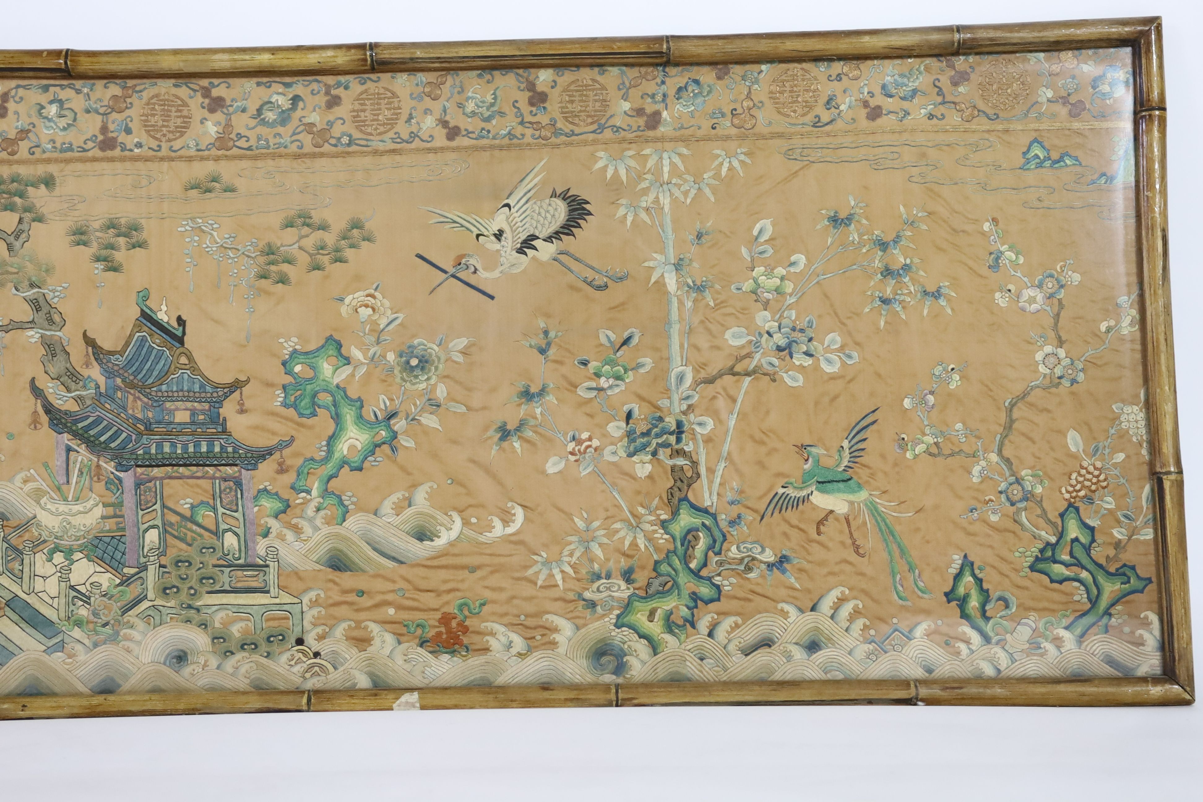 A Chinese apricot ground embroidered silk table frontal, late Qing dynasty, 58cm x 178cm, now trimmed and framed